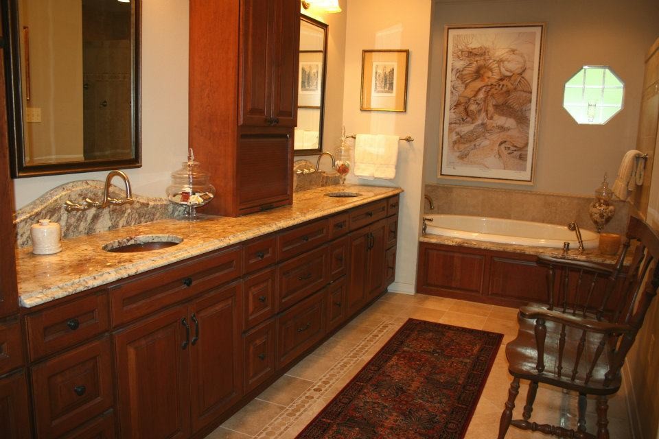 Klassisk inredning av ett mellanstort en-suite badrum, med luckor med upphöjd panel, bruna skåp, ett hörnbadkar, beige väggar, klinkergolv i keramik, ett nedsänkt handfat, granitbänkskiva och beiget golv