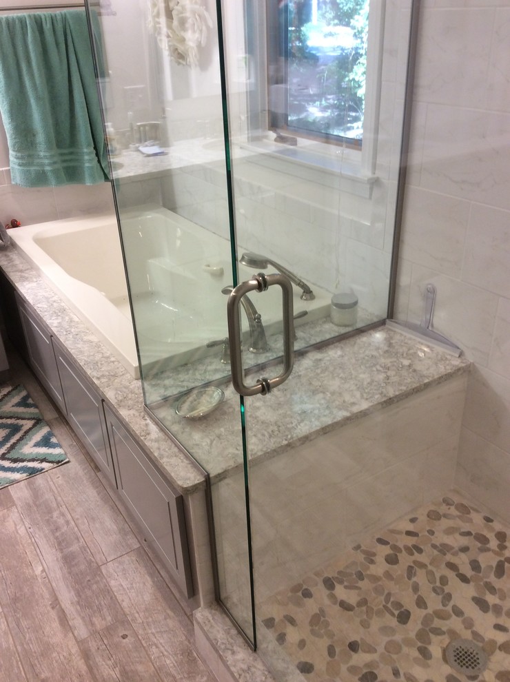 Cette image montre une salle de bain principale traditionnelle de taille moyenne avec une baignoire posée, une douche d'angle, des carreaux de porcelaine et un sol en galet.