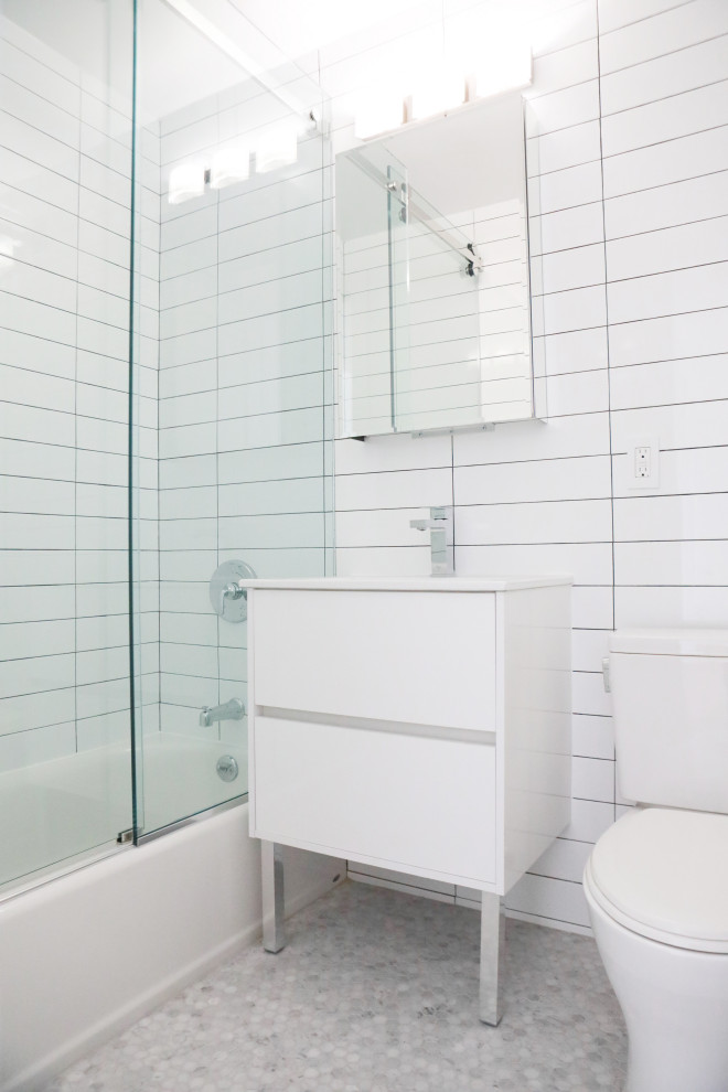 Exempel på ett litet modernt vit vitt badrum, med släta luckor, vita skåp, ett platsbyggt badkar, en dusch/badkar-kombination, en toalettstol med separat cisternkåpa, vit kakel, keramikplattor, vita väggar, mosaikgolv, ett nedsänkt handfat, grått golv och dusch med skjutdörr
