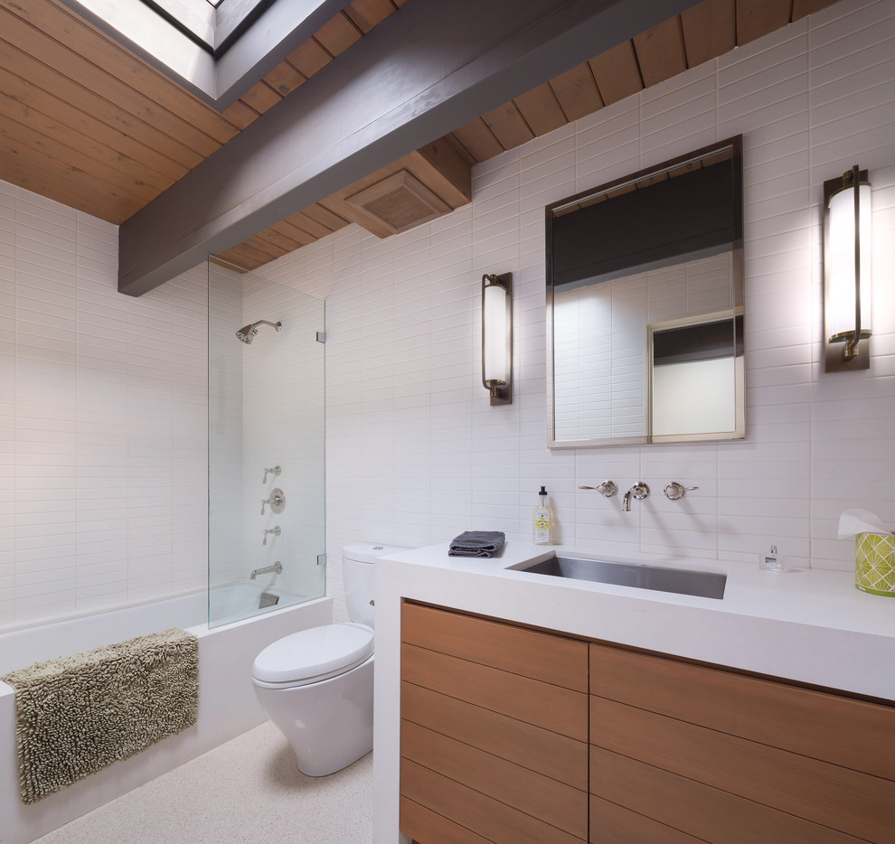 Idéer för att renovera ett funkis vit vitt badrum, med släta luckor, skåp i mellenmörkt trä, ett badkar i en alkov, en dusch/badkar-kombination, vit kakel, keramikplattor, vita väggar, linoleumgolv, ett undermonterad handfat, bänkskiva i kvarts, grått golv och med dusch som är öppen