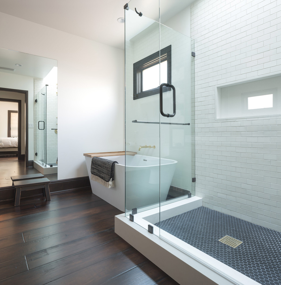 Klassisches Badezimmer mit freistehender Badewanne, Nasszelle, weißen Fliesen, Metrofliesen, weißer Wandfarbe, dunklem Holzboden, Falttür-Duschabtrennung und braunem Boden in Los Angeles