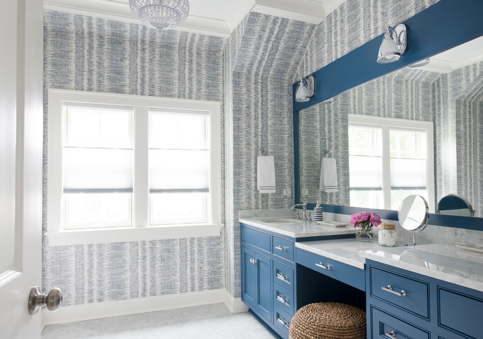 Idée de décoration pour une salle de bain marine avec un placard avec porte à panneau encastré, des portes de placard bleues, un mur multicolore, un lavabo encastré, un sol gris et un plan de toilette blanc.