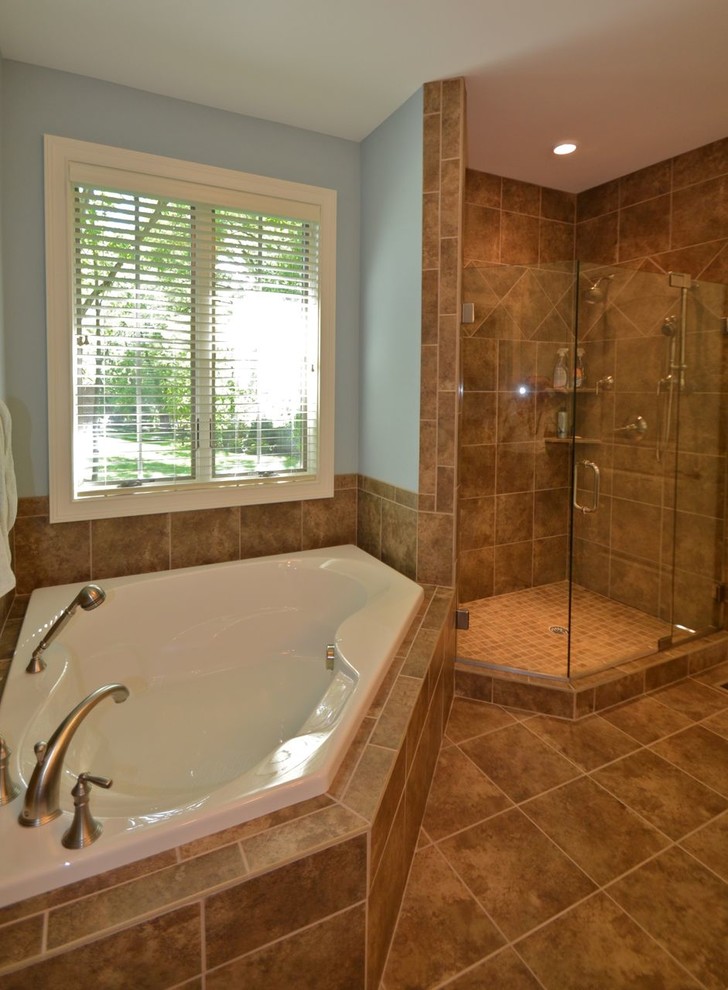 Imagen de cuarto de baño principal tradicional de tamaño medio con bañera esquinera, baldosas y/o azulejos beige, baldosas y/o azulejos de cerámica, paredes azules y suelo de baldosas de cerámica