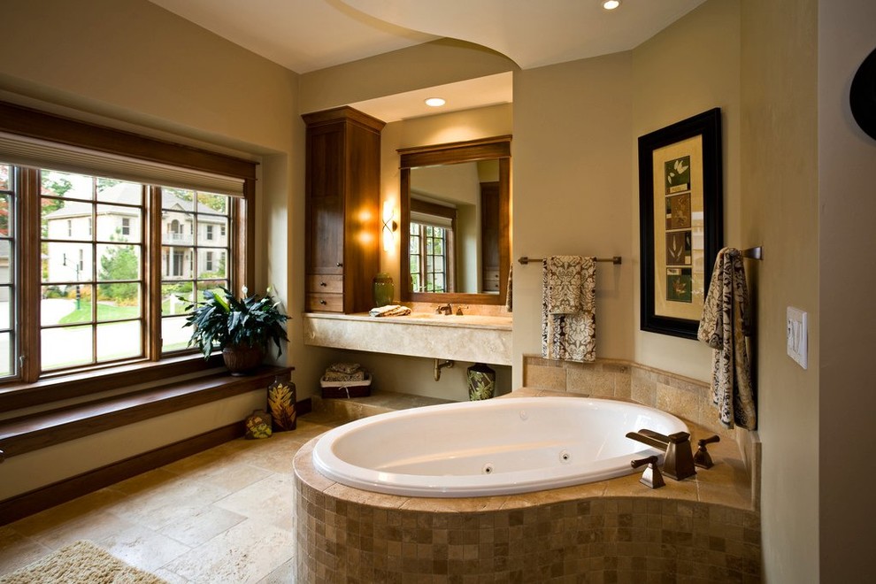 Klassisk inredning av ett mellanstort en-suite badrum, med ett platsbyggt badkar, beige kakel, stenkakel, beige väggar, klinkergolv i porslin, ett undermonterad handfat och beiget golv