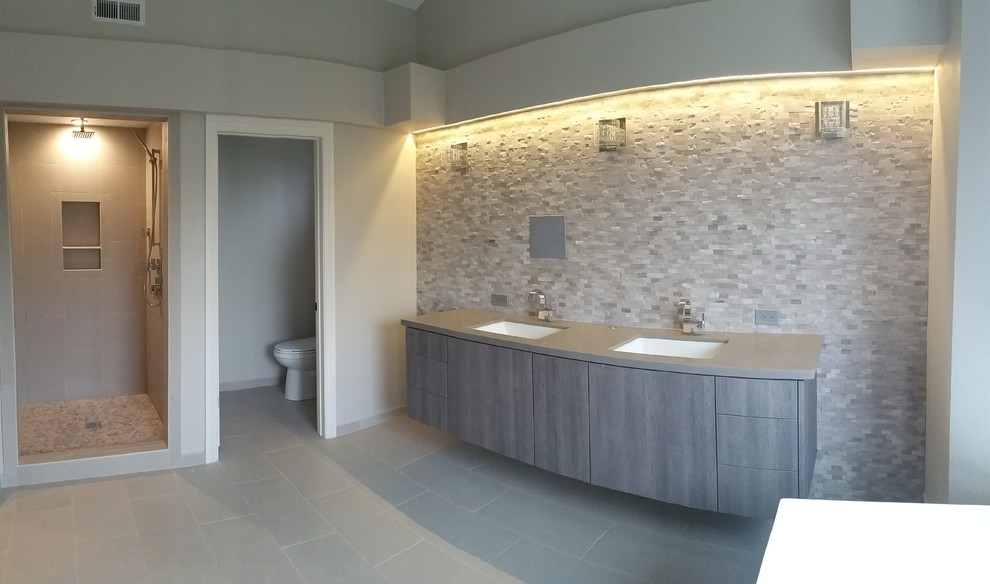 Large traditional ensuite bathroom in San Diego with a submerged sink, flat-panel cabinets, grey cabinets, solid surface worktops, an alcove shower, a two-piece toilet, grey tiles, stone tiles, grey walls and porcelain flooring.