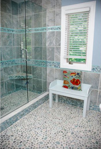 Cette photo montre une salle de bain tendance avec une douche ouverte, un carrelage gris, des carreaux de porcelaine et un sol en galet.
