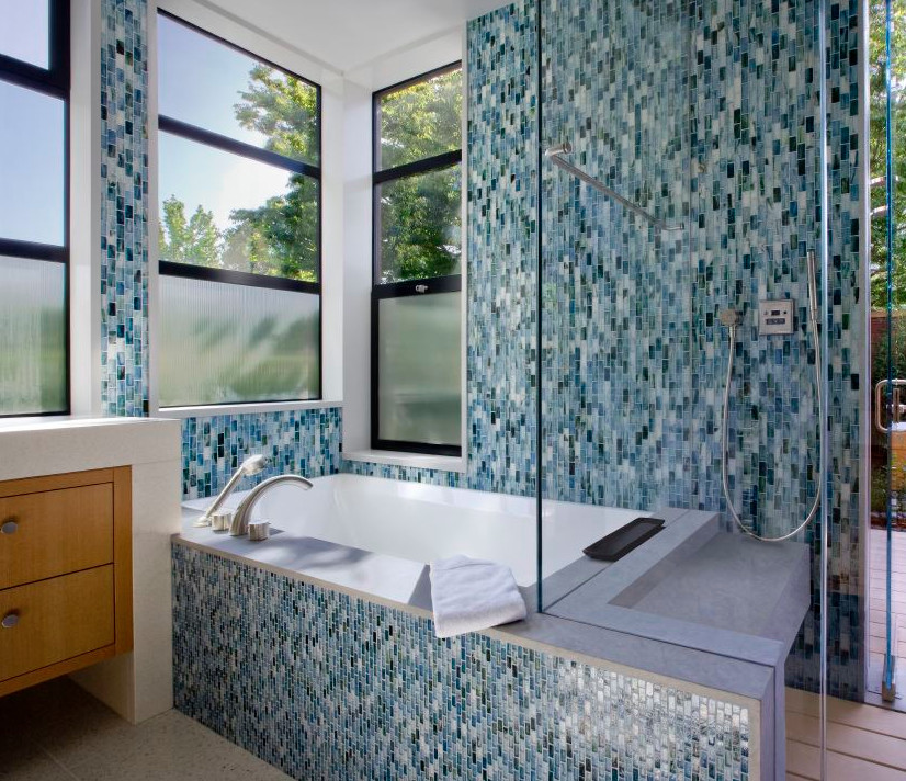 На фото: ванная комната в современном стиле с плоскими фасадами, светлыми деревянными фасадами, полновстраиваемой ванной, открытым душем, зеленой плиткой, плиткой мозаикой, белыми стенами, полом из керамогранита, врезной раковиной и столешницей из искусственного кварца с