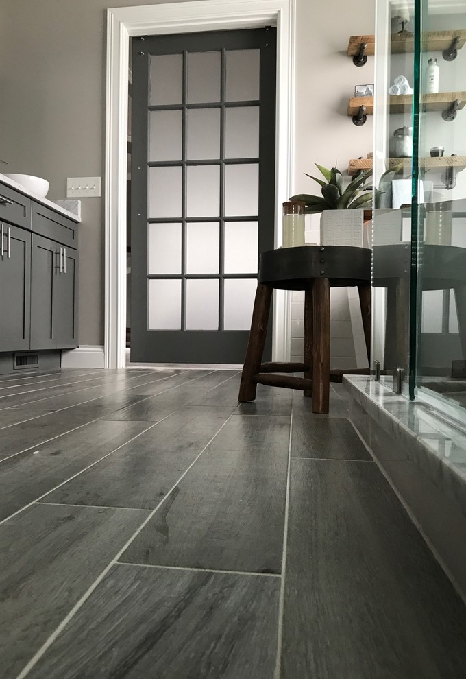 Example of a mid-sized transitional master white tile and subway tile laminate floor and gray floor bathroom design in Other with shaker cabinets, gray cabinets, a one-piece toilet, gray walls, a vessel sink and a hinged shower door