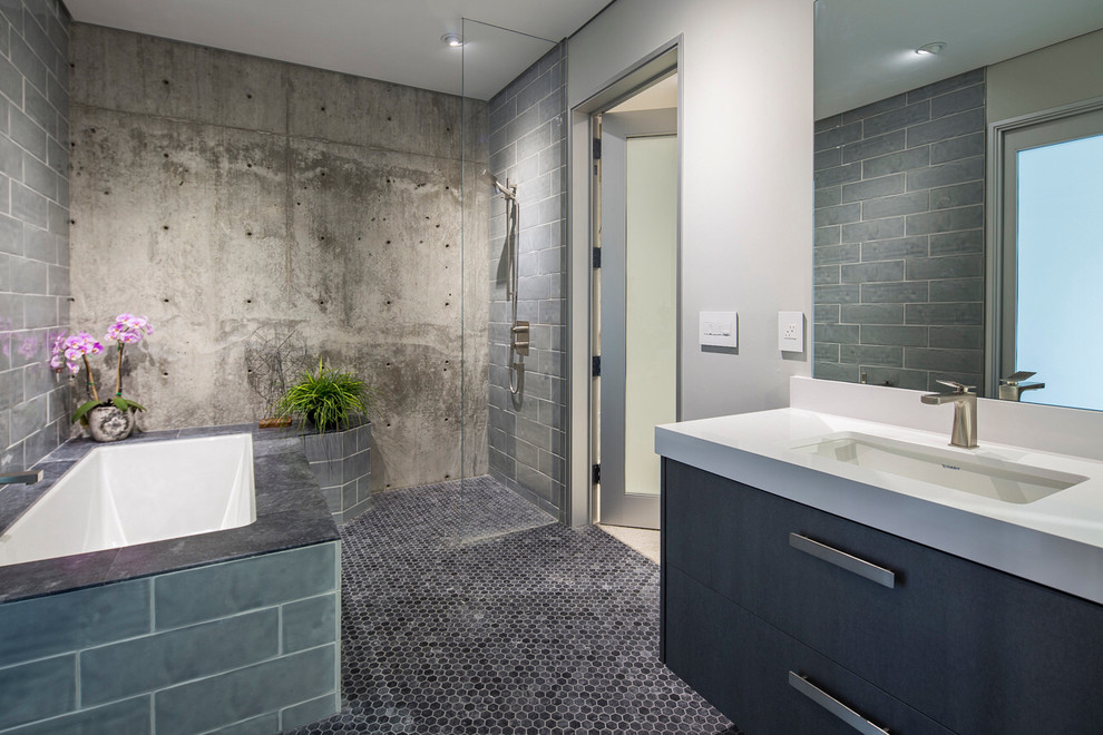 На фото: ванная комната в современном стиле с плоскими фасадами, полновстраиваемой ванной, открытым душем, серой плиткой, серыми стенами, врезной раковиной и серым полом с