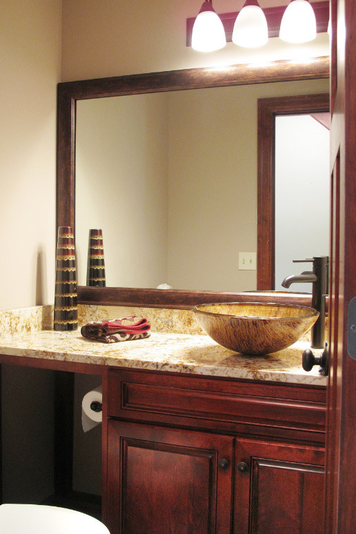 Esempio di una stanza da bagno american style di medie dimensioni con ante con bugna sagomata, ante in legno bruno, WC a due pezzi, pareti beige, lavabo a bacinella e top in granito