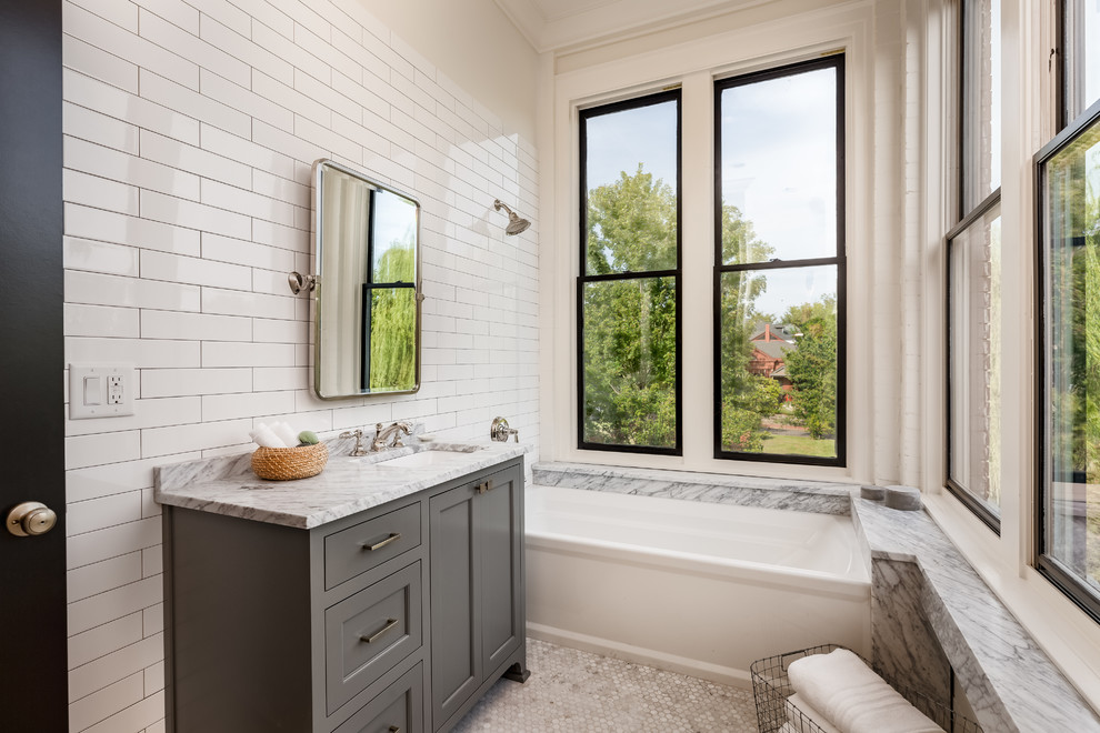 Inredning av ett klassiskt grå grått badrum med dusch, med skåp i shakerstil, grå skåp, ett badkar i en alkov, en dusch/badkar-kombination, vit kakel, vita väggar, mosaikgolv, ett undermonterad handfat, vitt golv och med dusch som är öppen