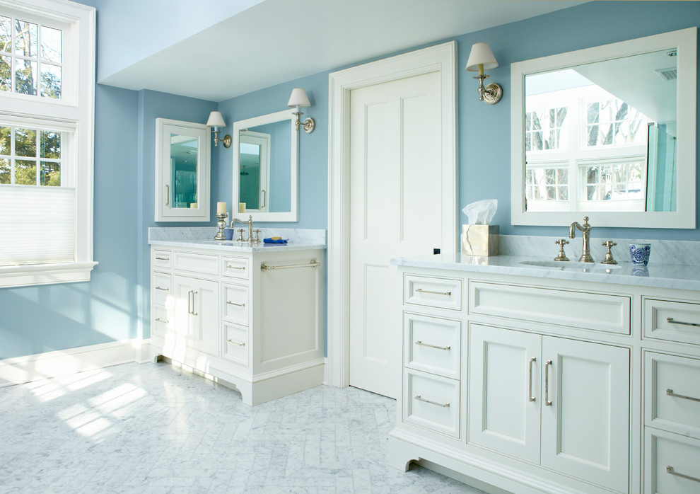 Inredning av ett klassiskt badrum, med ett undermonterad handfat, vita skåp, blå väggar och luckor med infälld panel