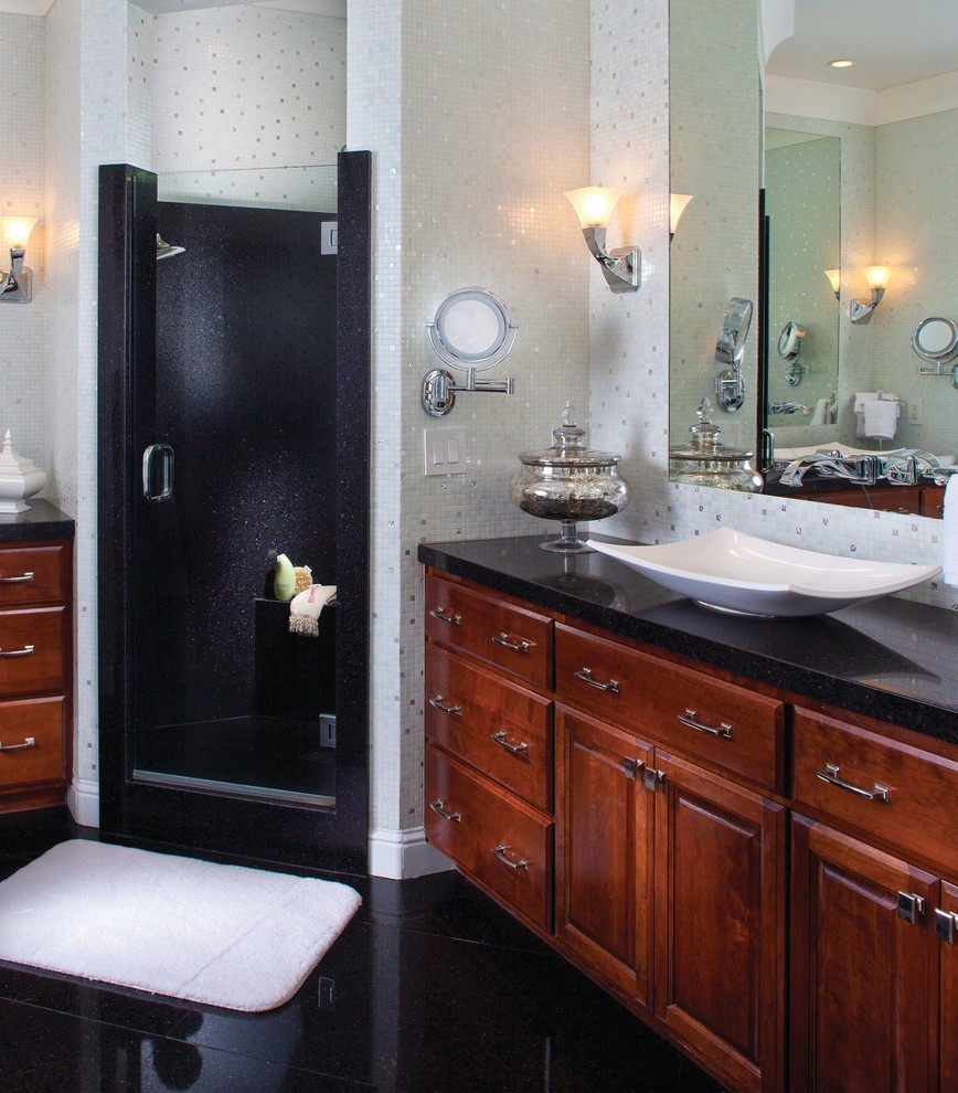 Photo of a medium sized eclectic ensuite bathroom in Atlanta with recessed-panel cabinets, brown cabinets, a corner shower, white tiles, glass tiles, a vessel sink, engineered stone worktops, a hinged door and black worktops.