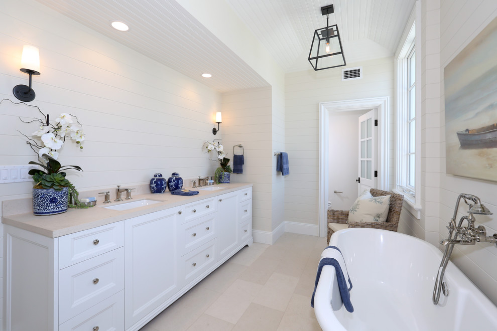 Inredning av ett stort en-suite badrum, med ett undermonterad handfat, släta luckor, vita skåp, ett fristående badkar och vita väggar