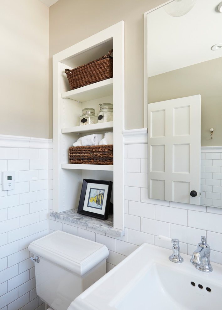 Klassisk inredning av ett litet badrum för barn, med ett badkar i en alkov, en dusch/badkar-kombination, en toalettstol med separat cisternkåpa, vit kakel, tunnelbanekakel, beige väggar, marmorgolv och ett piedestal handfat