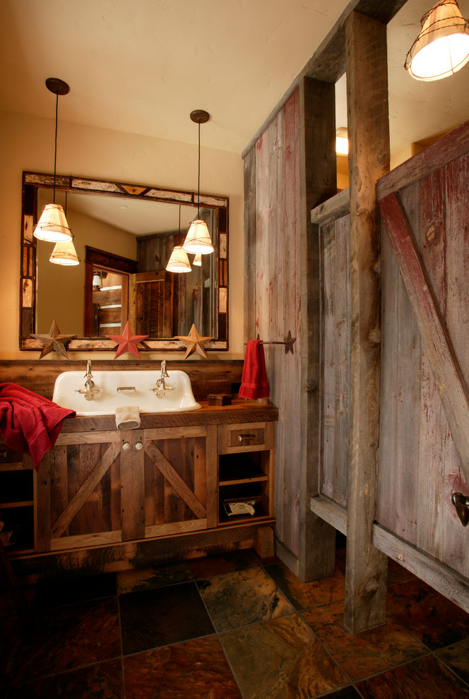Rustik inredning av ett mellanstort badrum med dusch, med ett avlångt handfat, skåp i slitet trä, beige väggar, brun kakel och luckor med infälld panel
