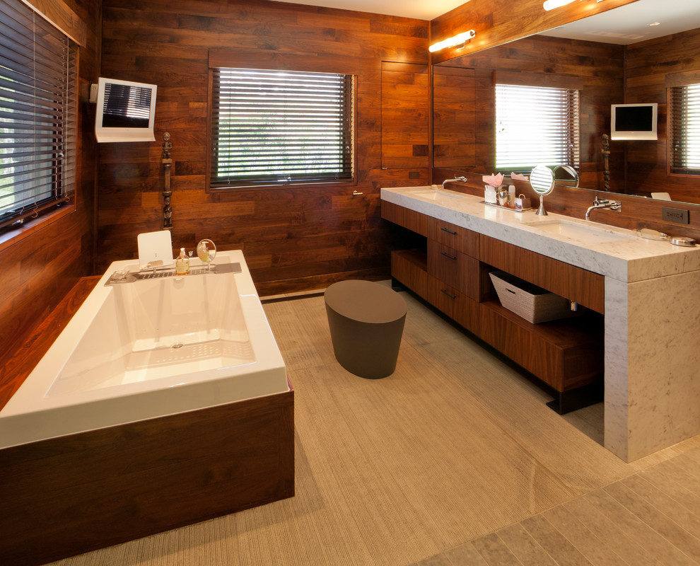 Modelo de cuarto de baño principal rural grande con armarios con paneles lisos, puertas de armario de madera oscura, bañera encastrada, baldosas y/o azulejos beige, paredes marrones, lavabo integrado y encimera de granito