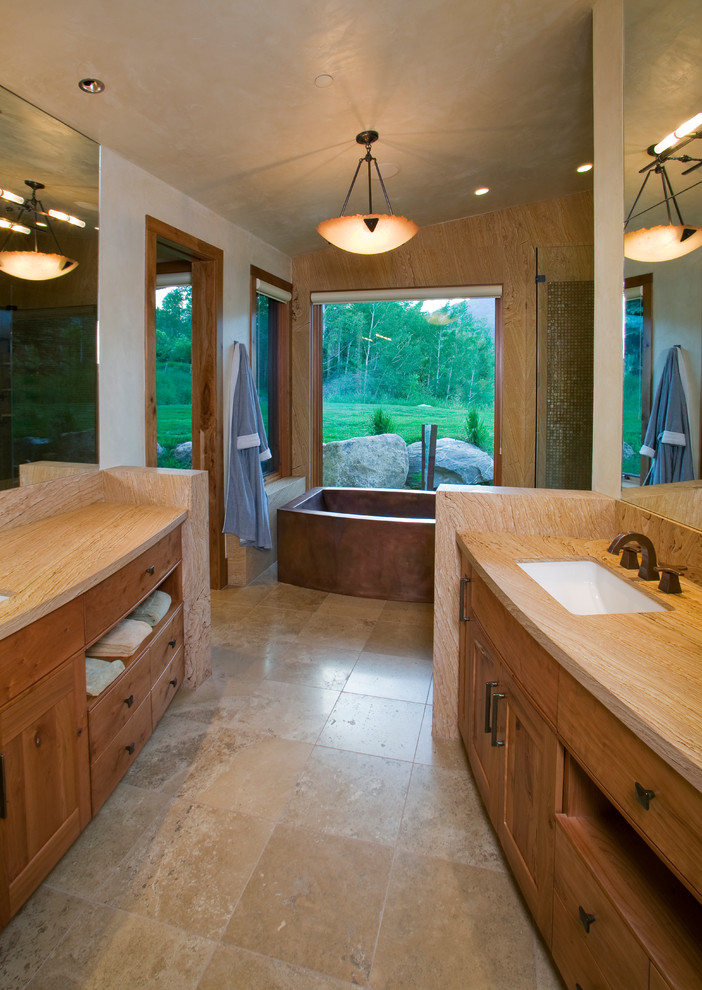 Diseño de cuarto de baño principal rústico grande con armarios estilo shaker, puertas de armario de madera clara, bañera exenta, baldosas y/o azulejos beige y lavabo bajoencimera