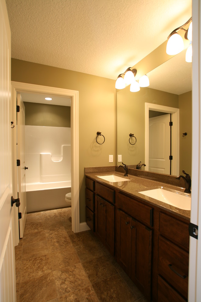 Cette image montre une salle de bain traditionnelle en bois brun avec un lavabo intégré, un placard à porte plane, un combiné douche/baignoire, un carrelage beige et des carreaux de céramique.