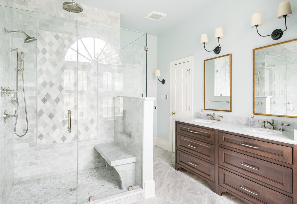 Ejemplo de cuarto de baño principal con armarios con rebordes decorativos, baldosas y/o azulejos de mármol, paredes azules, suelo de mármol, lavabo bajoencimera, encimera de mármol, ducha con puerta con bisagras, puertas de armario de madera en tonos medios, baldosas y/o azulejos blancos, suelo blanco y encimeras blancas