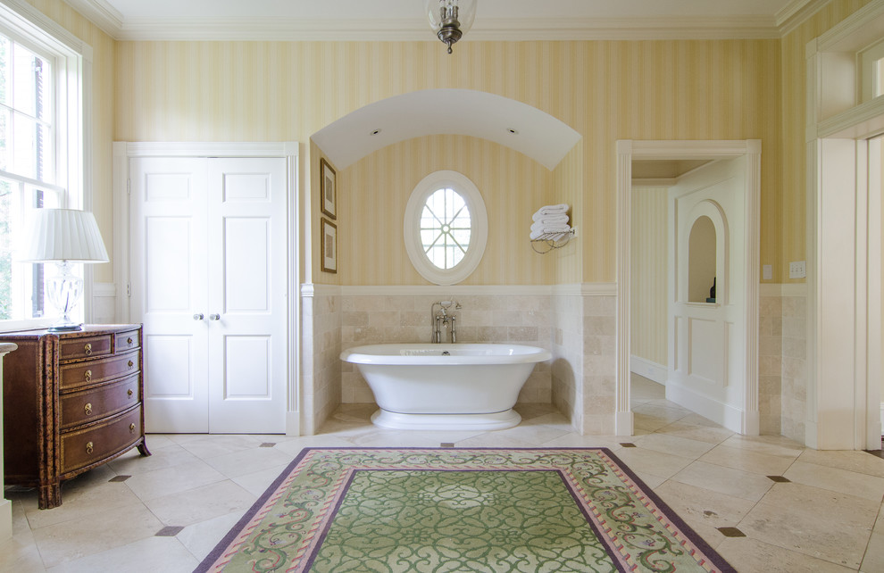 Idée de décoration pour une salle de bain avec une baignoire indépendante, un carrelage beige et une fenêtre.