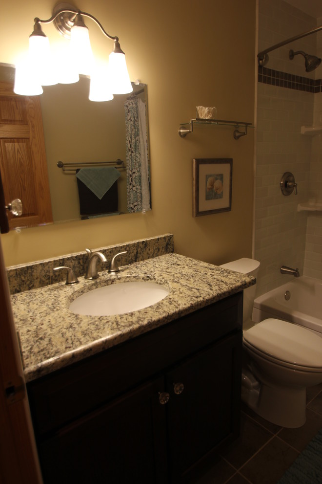 Inredning av ett klassiskt mellanstort badrum, med skåp i shakerstil, skåp i mörkt trä, ett badkar i en alkov, en dusch/badkar-kombination, vit kakel, tunnelbanekakel, beige väggar, ett undermonterad handfat och granitbänkskiva