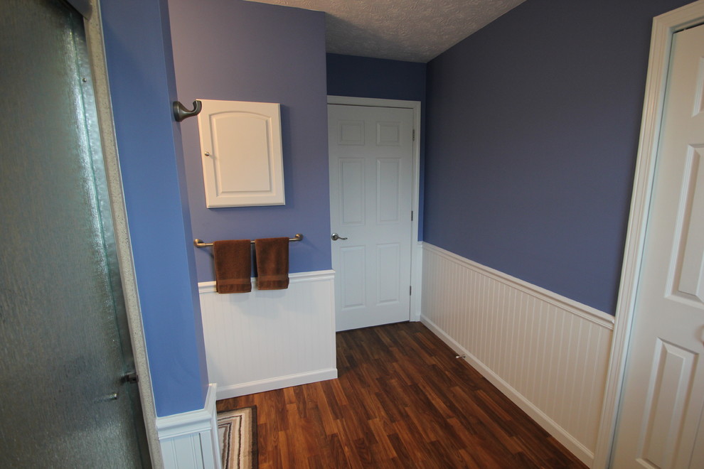 Réalisation d'une douche en alcôve tradition de taille moyenne avec un placard avec porte à panneau surélevé, des portes de placard blanches, un mur bleu, un sol en bois brun et un lavabo intégré.