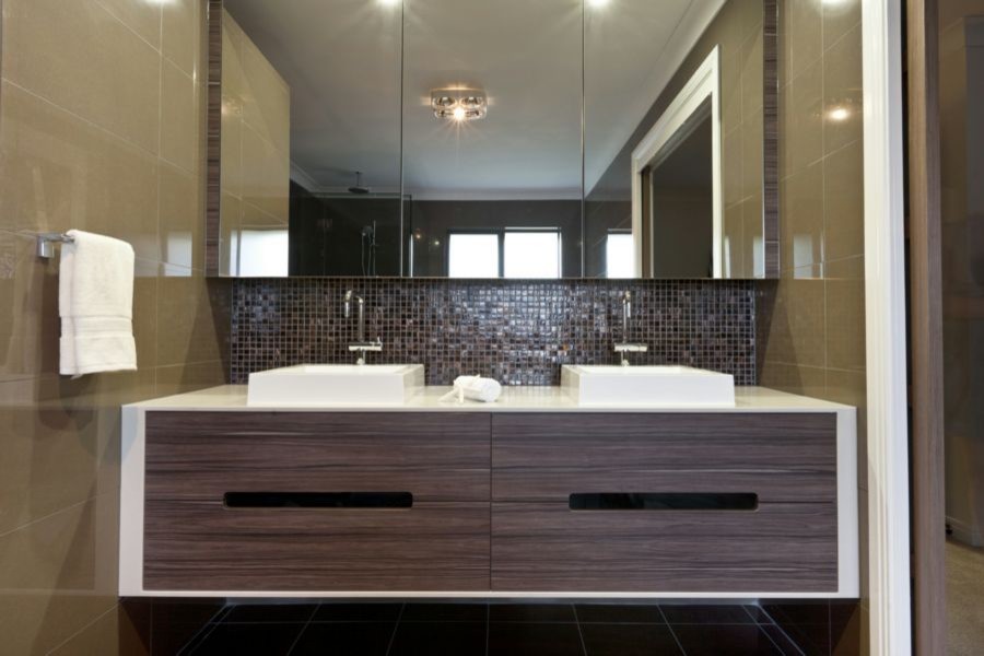 Photo of a modern bathroom in Raleigh with flat-panel cabinets, dark wood cabinets, brown tiles, mosaic tiles, beige walls, a vessel sink and white worktops.