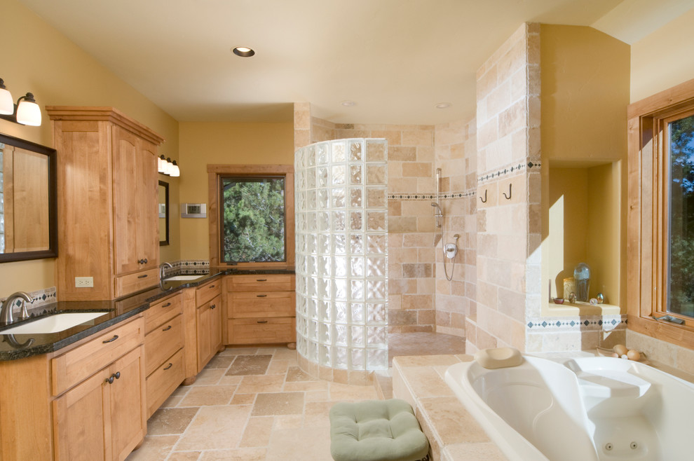 Aménagement d'une grande salle de bain principale craftsman en bois clair avec un placard à porte shaker, un bain bouillonnant, une douche ouverte, un carrelage beige, un carrelage de pierre, un mur beige, un sol en travertin, un lavabo encastré, un plan de toilette en granite, un sol beige et aucune cabine.