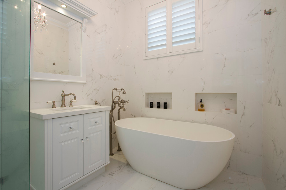 Immagine di una stanza da bagno minimalista con lavabo sottopiano, vasca freestanding, doccia ad angolo e pavimento in marmo