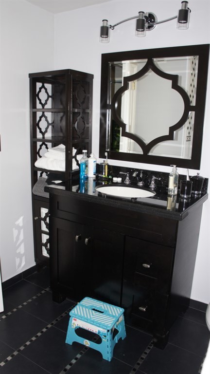 Photo of a medium sized contemporary ensuite bathroom in Los Angeles with an integrated sink, freestanding cabinets, dark wood cabinets, laminate worktops, a corner bath, a shower/bath combination, a one-piece toilet, black tiles, ceramic tiles, white walls and ceramic flooring.