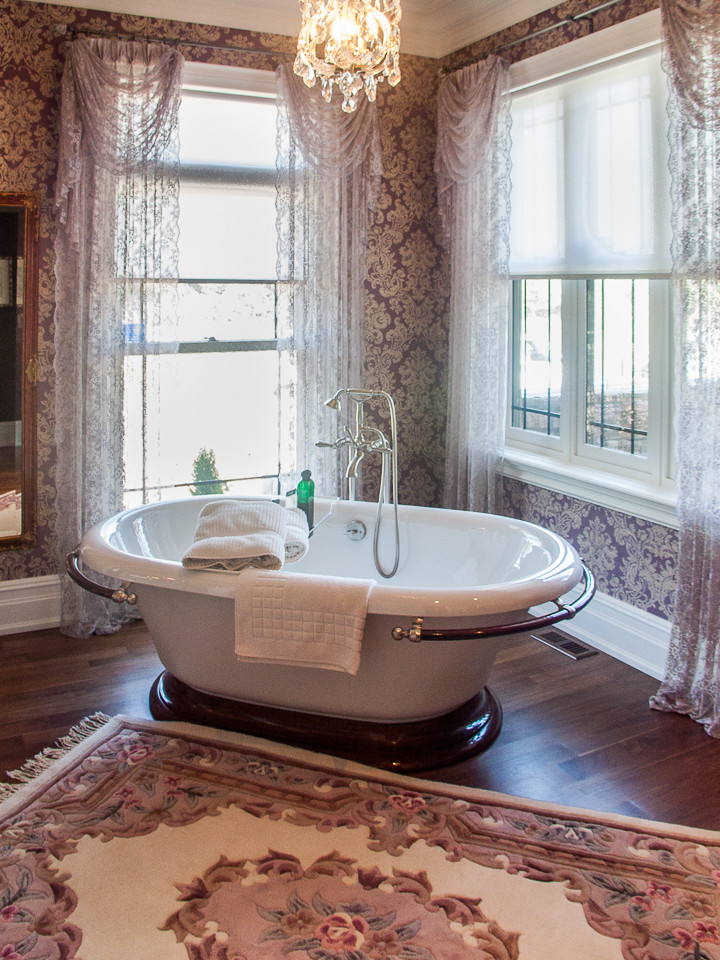 Großes Landhausstil Badezimmer En Suite mit freistehender Badewanne, lila Wandfarbe und braunem Holzboden in Toronto