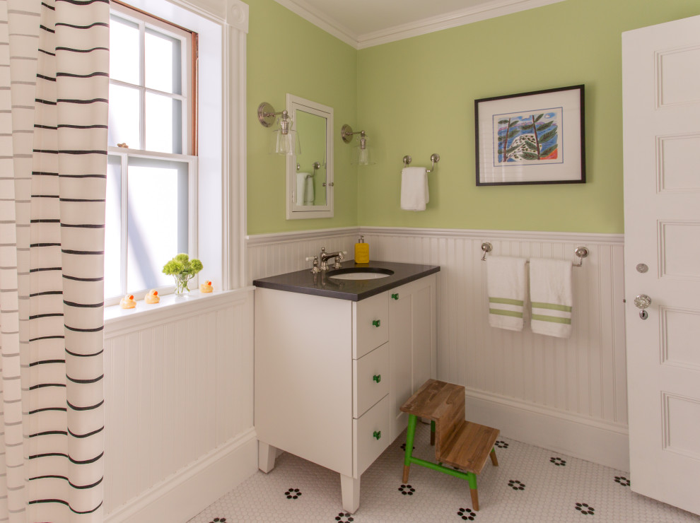 Modelo de cuarto de baño infantil clásico con puertas de armario blancas, paredes verdes, suelo con mosaicos de baldosas, lavabo bajoencimera, suelo blanco, encimeras negras y armarios estilo shaker