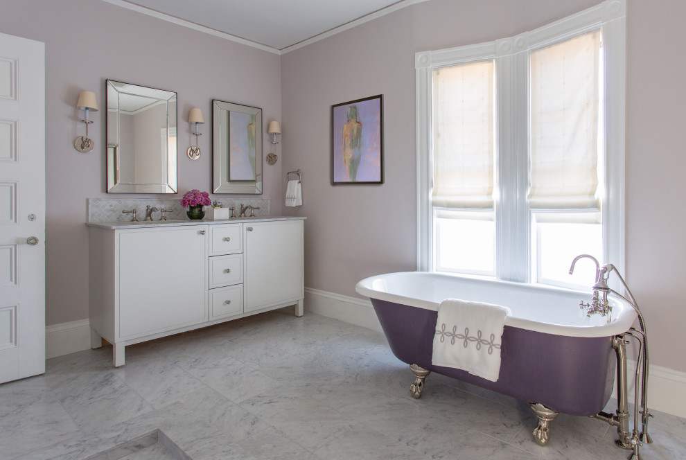 На фото: главная ванная комната в стиле неоклассика (современная классика) с белыми фасадами, ванной на ножках, фиолетовыми стенами, врезной раковиной, серым полом, серой столешницей и плоскими фасадами