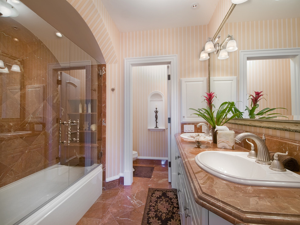 Свежая идея для дизайна: главная ванная комната среднего размера в классическом стиле с фасадами с выступающей филенкой, белыми фасадами, ванной в нише, душем над ванной, унитазом-моноблоком, коричневой плиткой, каменной плиткой, розовыми стенами, полом из травертина, накладной раковиной и столешницей из гранита - отличное фото интерьера