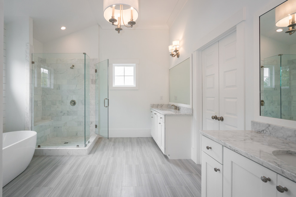 Photo of a large modern ensuite bathroom in Atlanta with white cabinets, a freestanding bath, a corner shower, white walls, light hardwood flooring, a built-in sink, grey floors, a hinged door and grey worktops.