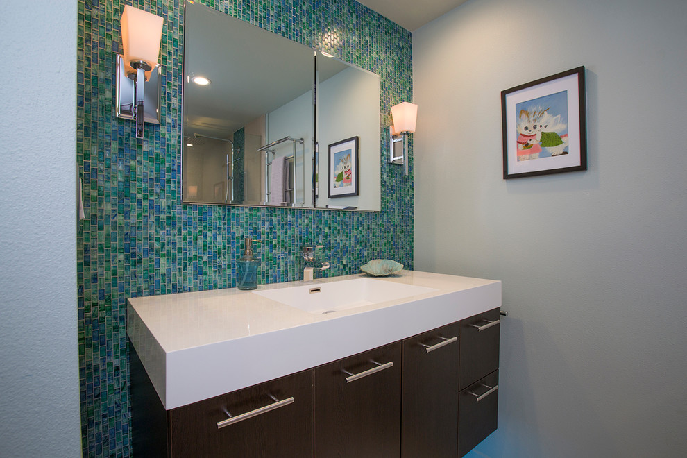 На фото: главная ванная комната среднего размера в стиле неоклассика (современная классика) с плоскими фасадами, коричневыми фасадами, зеленой плиткой, стеклянной плиткой, серыми стенами, монолитной раковиной и белой столешницей с