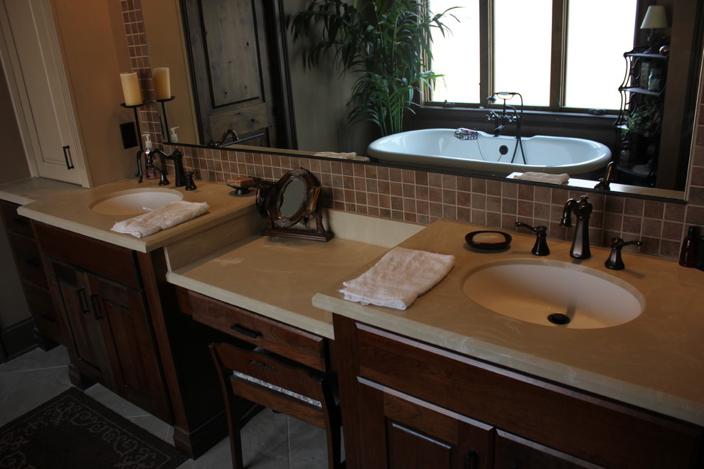 Bild på ett mellanstort vintage en-suite badrum, med luckor med upphöjd panel, bruna skåp, ett fristående badkar, brun kakel, keramikplattor, klinkergolv i keramik, ett undermonterad handfat, bänkskiva i kvarts och grått golv