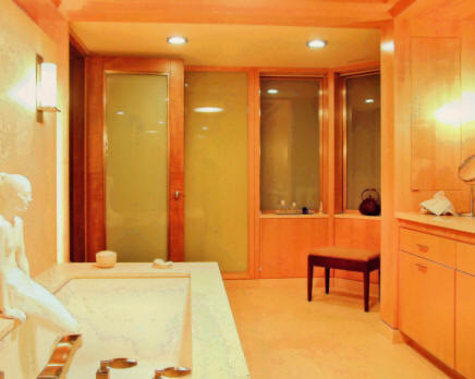 Imagen de cuarto de baño principal moderno extra grande con armarios con paneles lisos, puertas de armario de madera clara, bañera encastrada sin remate, suelo de piedra caliza, lavabo integrado y encimera de piedra caliza
