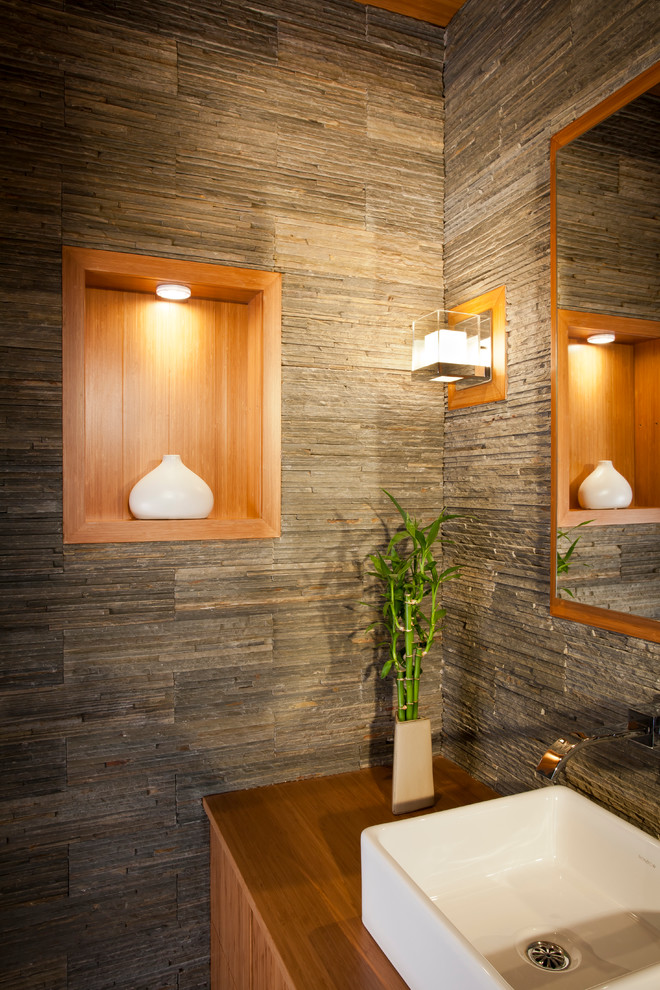 Idées déco pour une petite salle de bain moderne en bois brun avec une grande vasque, un placard à porte plane, un plan de toilette en bois, WC à poser, un carrelage gris, un carrelage de pierre, un mur gris et un sol en ardoise.