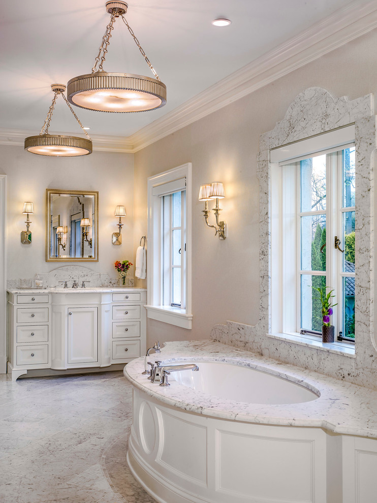 Стильный дизайн: главная ванная комната в классическом стиле с фасадами с выступающей филенкой, белыми фасадами, отдельно стоящей ванной, душем в нише, бежевыми стенами, мраморным полом, врезной раковиной, мраморной столешницей, белым полом и душем с раздвижными дверями - последний тренд