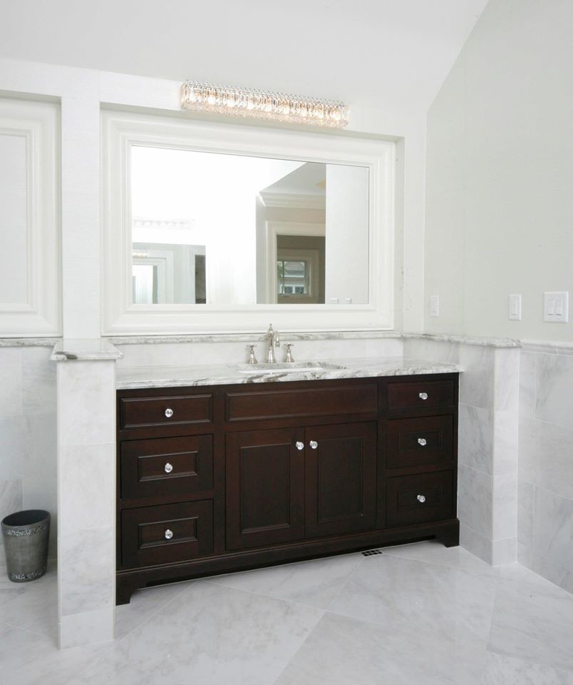 Inredning av ett klassiskt mycket stort badrum, med ett undermonterad handfat, luckor med infälld panel, skåp i mörkt trä, marmorbänkskiva, ett fristående badkar, en dubbeldusch, en toalettstol med hel cisternkåpa, grå kakel, stenkakel, beige väggar och marmorgolv