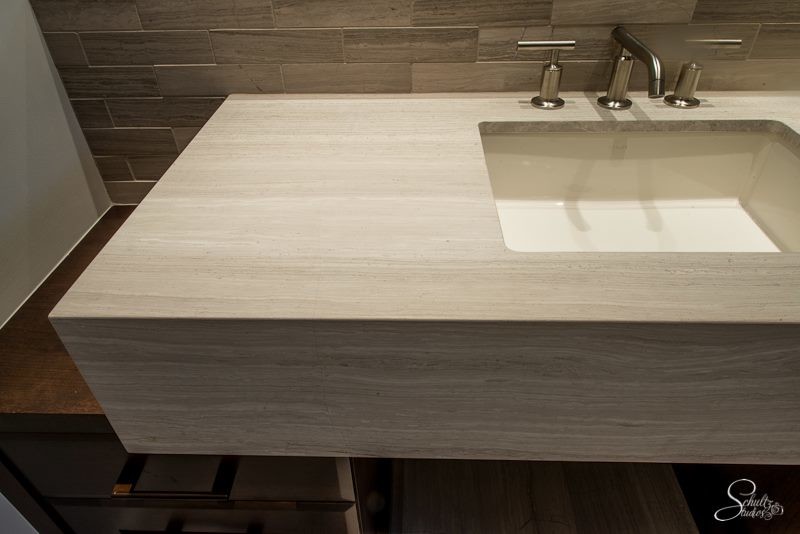 Modern inredning av ett mellanstort badrum med dusch, med släta luckor, skåp i mörkt trä, en dusch i en alkov, beige kakel, stenkakel, vita väggar, klinkergolv i keramik, ett nedsänkt handfat och bänkskiva i kalksten