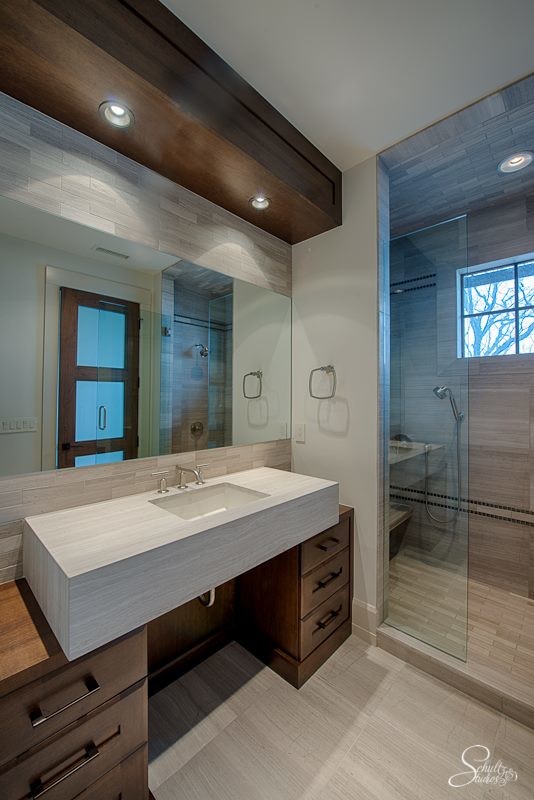 Idéer för ett mellanstort modernt badrum med dusch, med släta luckor, skåp i mörkt trä, en dusch i en alkov, beige kakel, stenkakel, vita väggar, klinkergolv i keramik, ett nedsänkt handfat och bänkskiva i kalksten