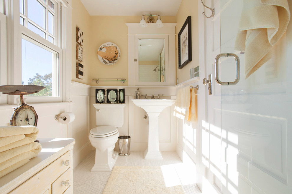 Idéer för att renovera ett vintage badrum med dusch, med beige skåp, en hörndusch, en toalettstol med separat cisternkåpa, gula väggar, mosaikgolv, ett piedestal handfat, vitt golv och dusch med gångjärnsdörr