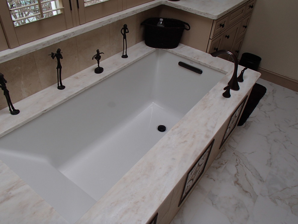 Ispirazione per una stanza da bagno padronale design di medie dimensioni con ante con riquadro incassato, ante in legno chiaro, vasca sottopiano, piastrelle beige, piastrelle di cemento, pareti beige, pavimento in marmo e top in marmo