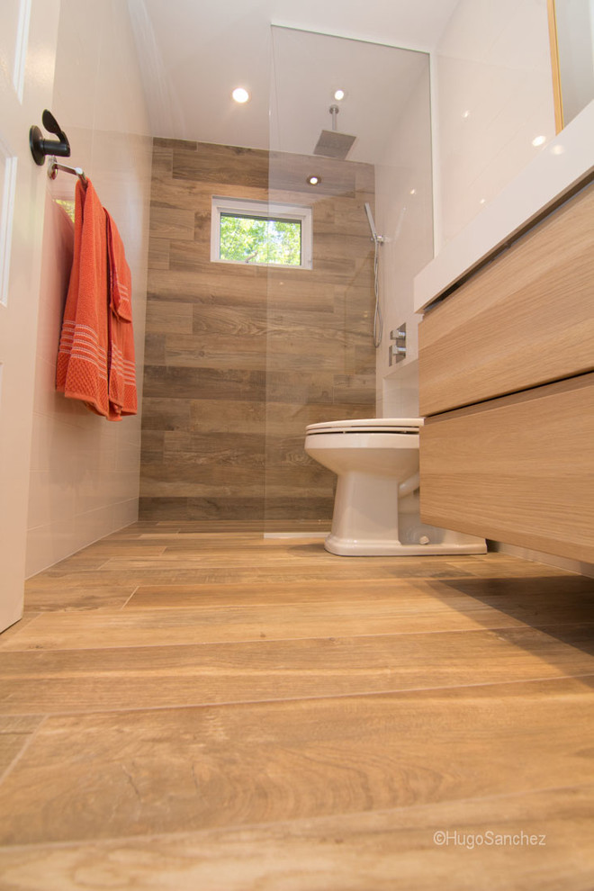 Photo of a small contemporary bathroom in Montreal with an integrated sink, flat-panel cabinets, light wood cabinets, a built-in shower, a one-piece toilet, white walls and porcelain flooring.
