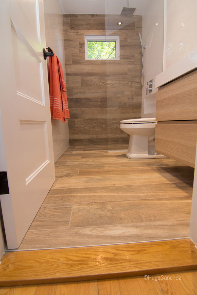 This is an example of a small contemporary family bathroom in Montreal with an integrated sink, flat-panel cabinets, light wood cabinets, a built-in shower, a one-piece toilet, white walls and porcelain flooring.