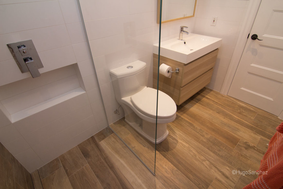 Inspiration for a small contemporary family bathroom in Montreal with an integrated sink, flat-panel cabinets, light wood cabinets, a built-in shower, a one-piece toilet, white walls and porcelain flooring.