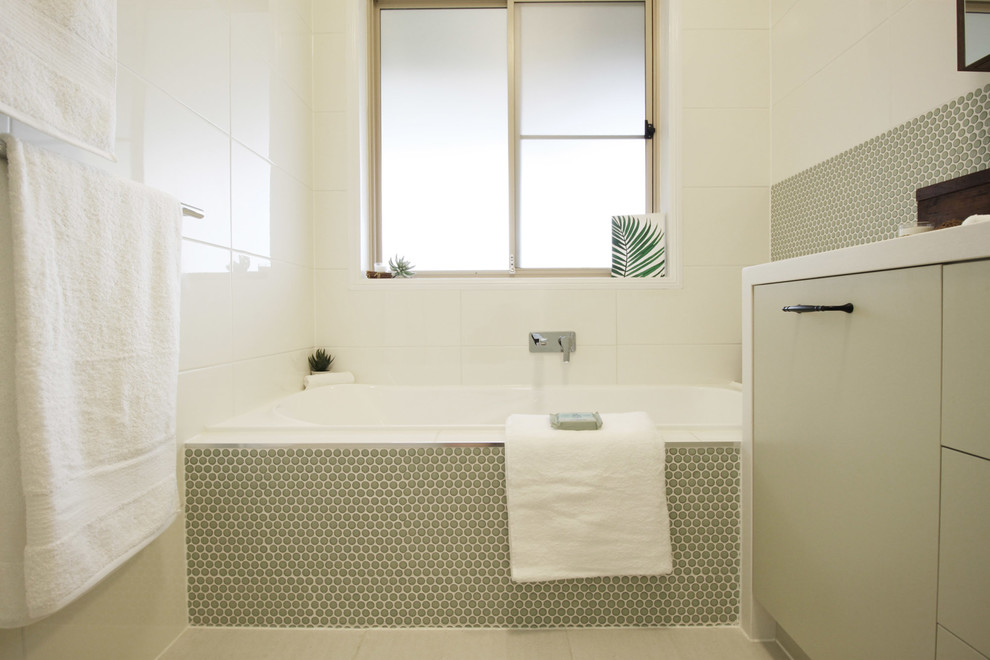 Design ideas for a small contemporary family bathroom in Brisbane with flat-panel cabinets, green cabinets, a built-in bath, a built-in shower, a two-piece toilet, white tiles, mosaic tiles, white walls, porcelain flooring, a vessel sink, engineered stone worktops, beige floors, a hinged door and white worktops.
